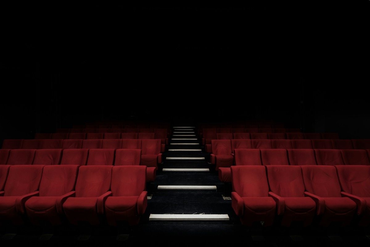 Rows of empty red seats in a darkened theatre