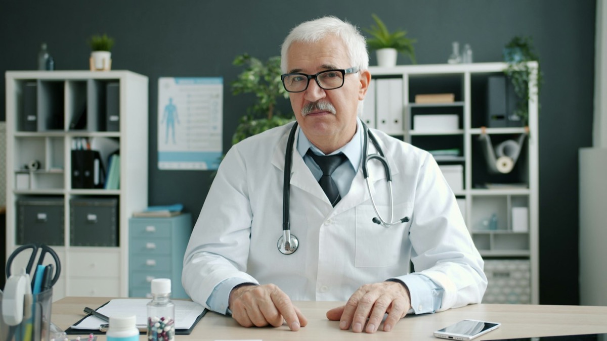 A doctor seated at a desk in a consulting room